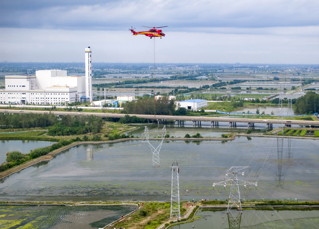 9月24日，直升機(jī)在江蘇省興化市昌榮鎮(zhèn)上空協(xié)助鐵塔架設(shè)作業(yè)（無(wú)人機(jī)照片）。新華社發(fā)（湯德宏攝）