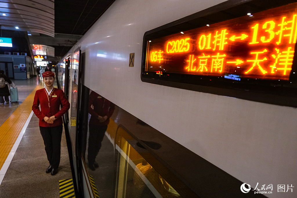 12月30日，乘務(wù)人員在北京南開往天津的C2025次列車立崗迎接旅客乘車。