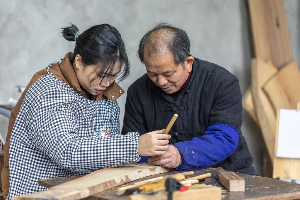 1月14日，在重慶市梁平區(qū)屏錦鎮(zhèn)，梁平木版年畫國家級代表性傳承人徐家輝（右）指導(dǎo)學(xué)生熊彩汝梁平木版年畫技藝。