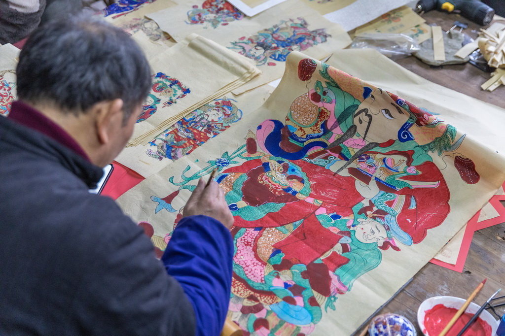 1月14日，在重慶市梁平區(qū)屏錦鎮(zhèn)，梁平木版年畫國家級代表性傳承人徐家輝在工作室內為年畫描色。